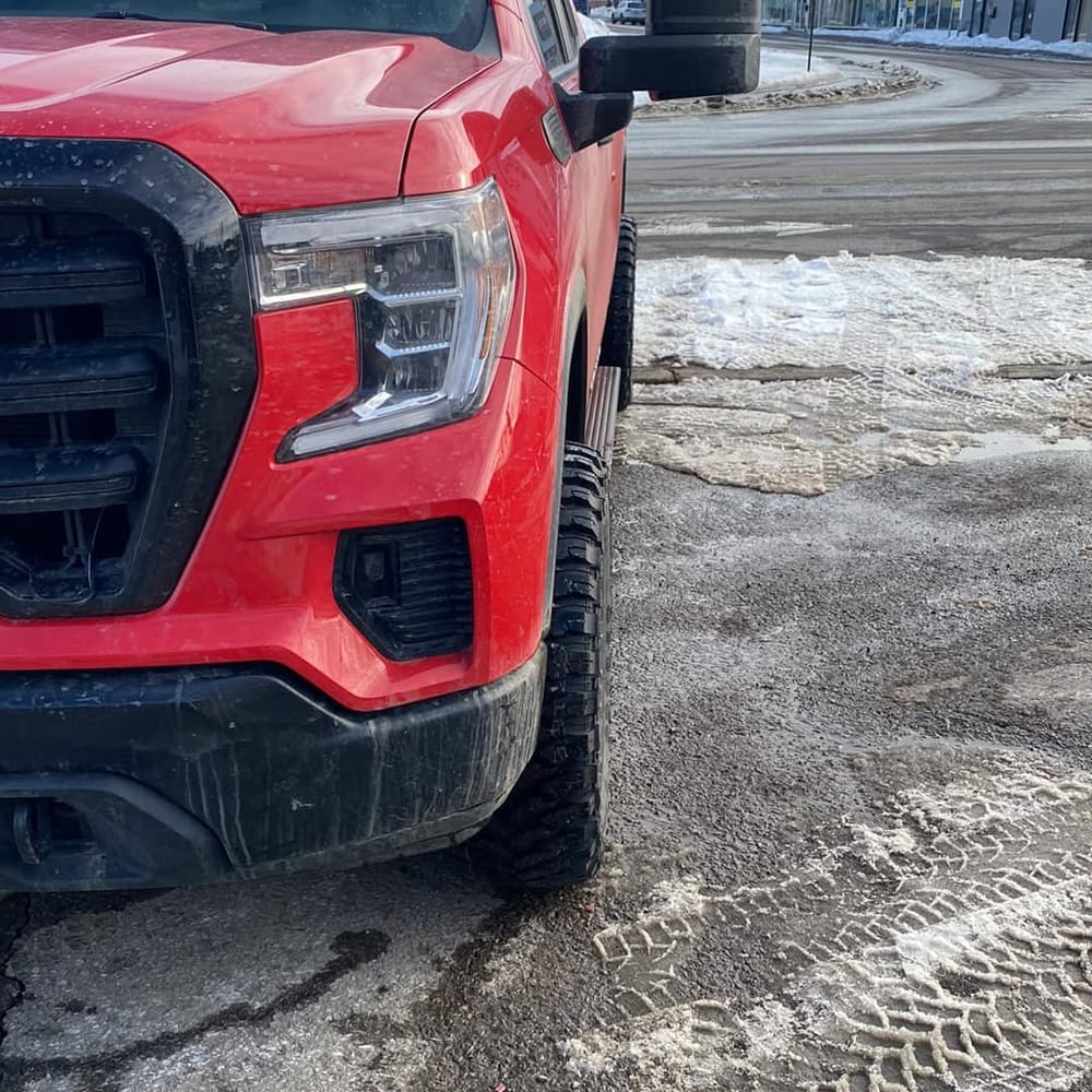 Avant du même Sierra rouge sur une rue enneigée, chaussé de pneus d’hiver cloutés.